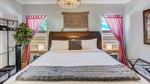 A neatly arranged bedroom with a large bed, a hanging light fixture, and a window with curtains. - Potter's Peak (Cascade)