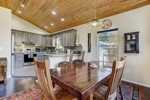 A spacious kitchen with wooden cabinets, a dining table with chairs, and a large island. - Potter's Peak (Cascade)