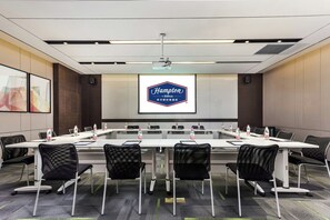 A conference room with a long table, chairs, a projector screen, and water bottles. - Hampton Hilton Xuzhou Yunlong Mountain (Xuzhou)