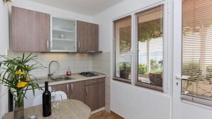 Una cocina compacta con armarios de madera, una estufa a gas y una mesa de comedor con un jarrón de flores.