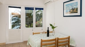 A dining area with a table set for two, a bottle of wine, and a vase with a plant.
