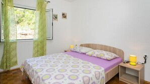 A bedroom with a bed, a nightstand, and a window with curtains.