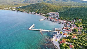A coastal town with a pier extending into the sea, surrounded by lush green hills.