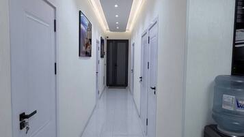 A hallway with white doors, recessed lighting, and a water dispenser on the right.