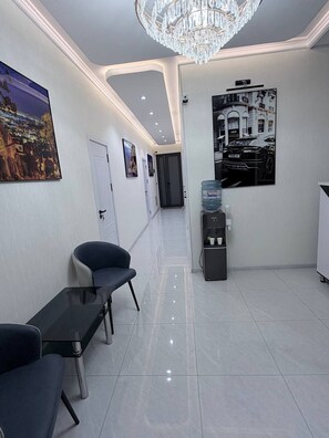 Un espace d’accueil d’hôtel comprenant un distributeur d’eau, des sièges et un lustre.