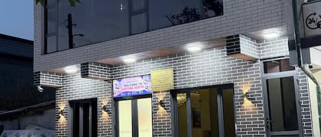Une auberge de jeunesse avec une enseigne bien visible indiquant « AUBERGE », une banderole d’accueil et une façade en briques.