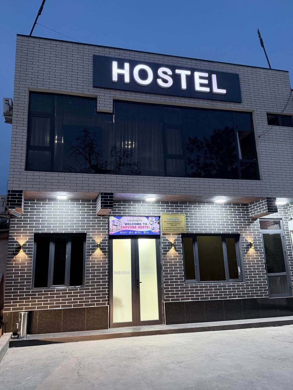 A hostel with a prominent 'HOSTEL' sign, a welcome banner, and a door with a glass panel.