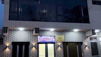 A hostel with a prominent 'HOSTEL' sign, a welcome banner, and a door with a glass panel.