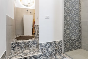 Une salle de bain avec des carreaux décorés, une baignoire blanche et un espace douche.