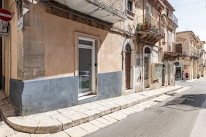 Un bâtiment avec une porte fermée, une fenêtre et un balcon orné de plantes en pot.