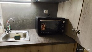 A compact kitchen with a sink, a toaster, and a blue towel hanging on the wall.