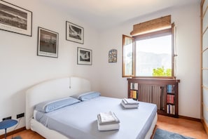 Ein Schlafzimmer mit einem Bett, einer Heizung, einem Fenster mit Blick und gerahmten Bildern an der Wand.