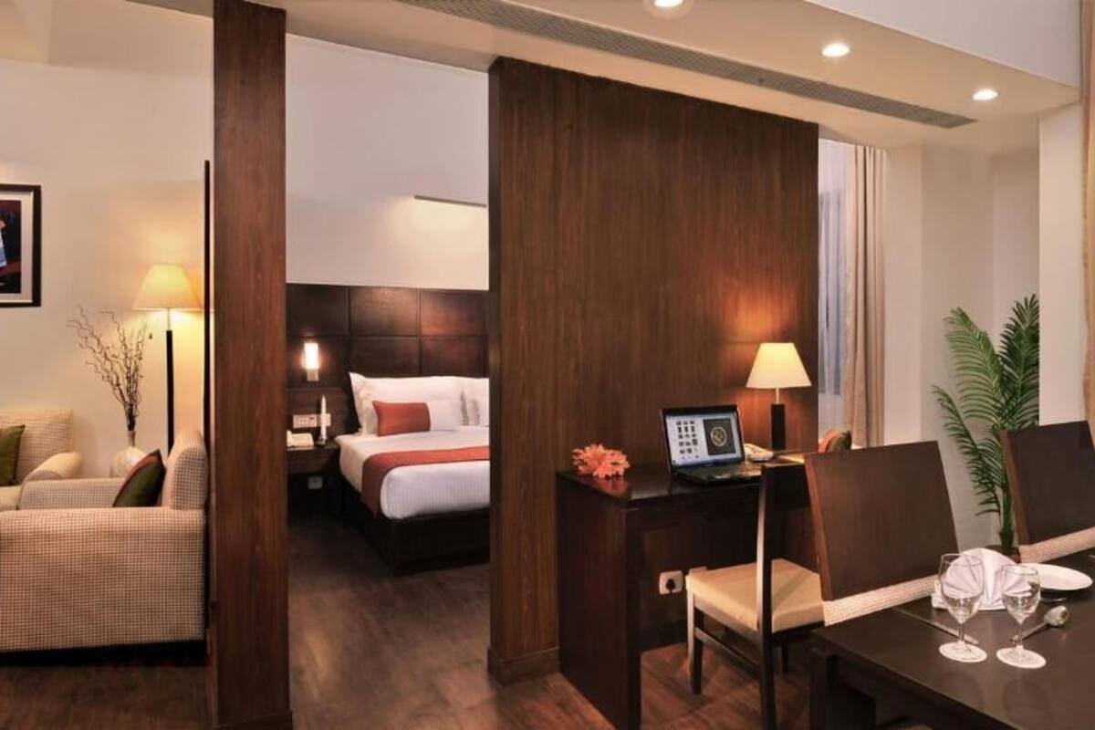Ein Hotelzimmer mit Bett, Schreibtisch mit Computer, Esstisch für zwei Personen und einem Stuhl.