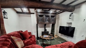 Ein gemütliches Wohnzimmer mit einem roten Sofa, einem Holzschrank, einem Kamin und einem an der Wand befestigten Flachbildfernseher.