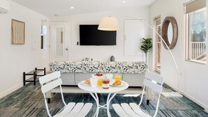 Una cocina moderna con comedor, televisor de pantalla plana y espacio para el desayuno, con croissants, jugo y un bol de fruta.