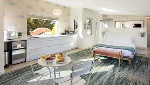 Una habitación de hotel moderna con kitchenette, zona de comedor y una cama grande.