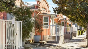 Una hilera de casas con cercas blancas y una planta grande en maceta en el centro.