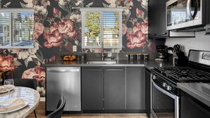 Ett modernt kök med en central köksö, rostfria vitvaror och en tapet med blommönster.