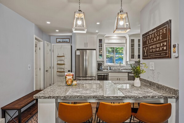 A modern kitchen with granite countertops, stainless steel appliances, and pendant lighting.