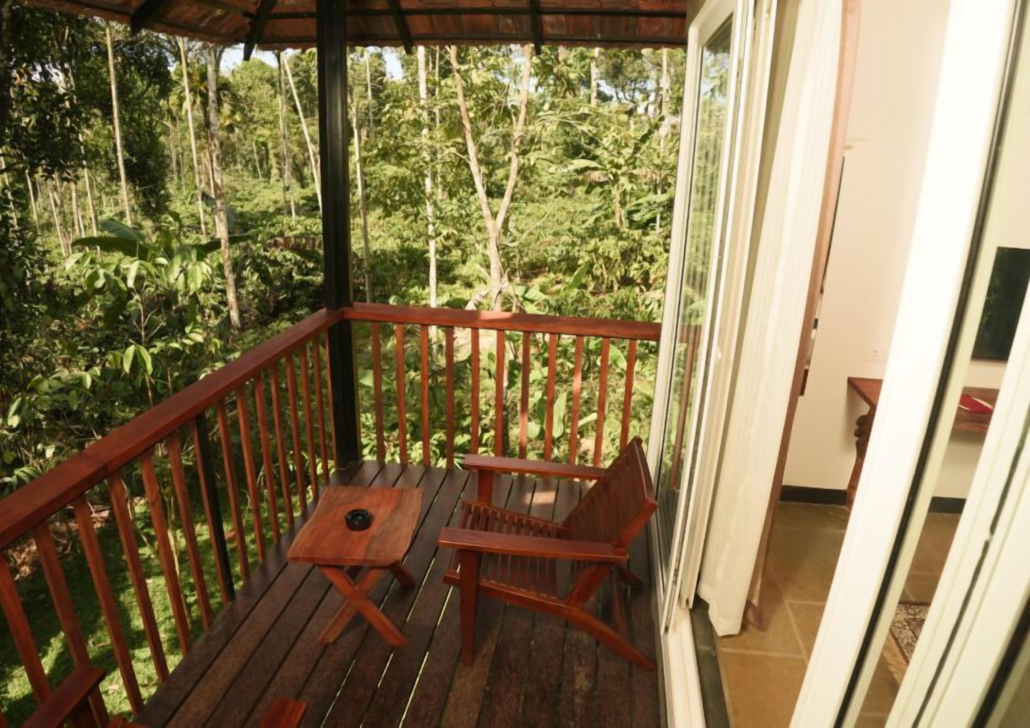 A wooden deck with a table and chairs, surrounded by lush greenery.