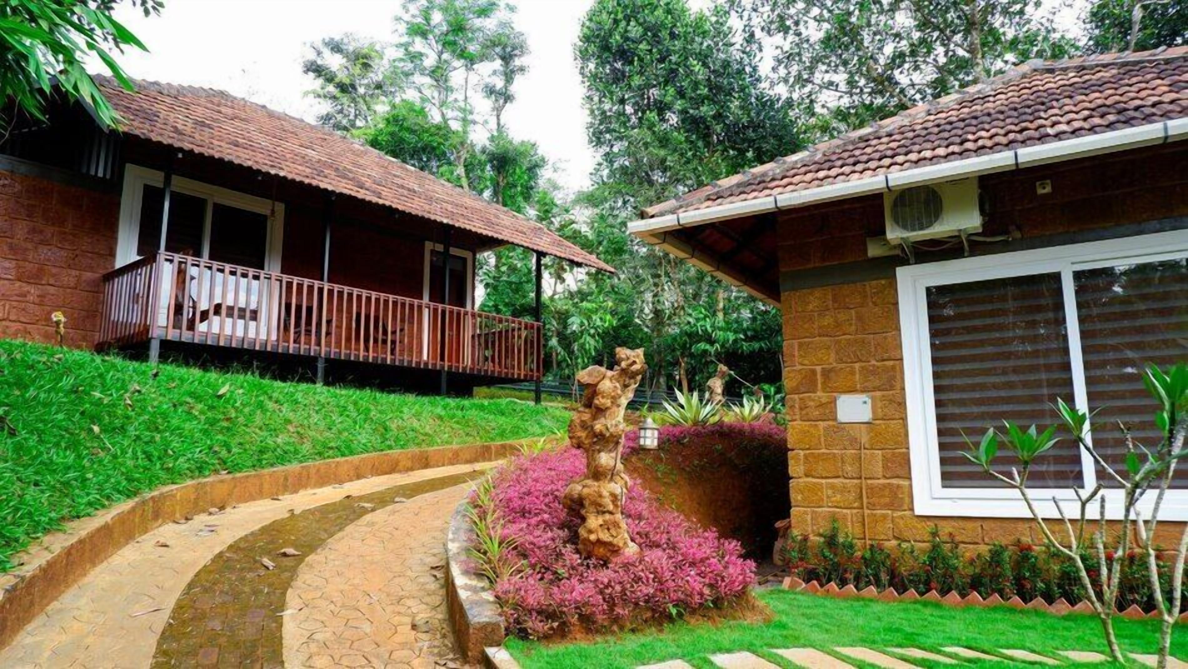 Una casa con balcón y jardín, que incluye una escultura de roca.