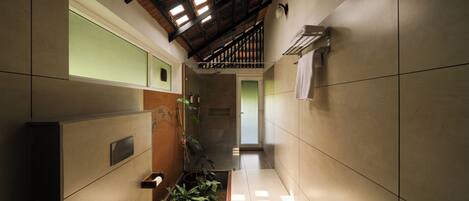 A narrow hallway with a toilet, a sink, and a shower area.
