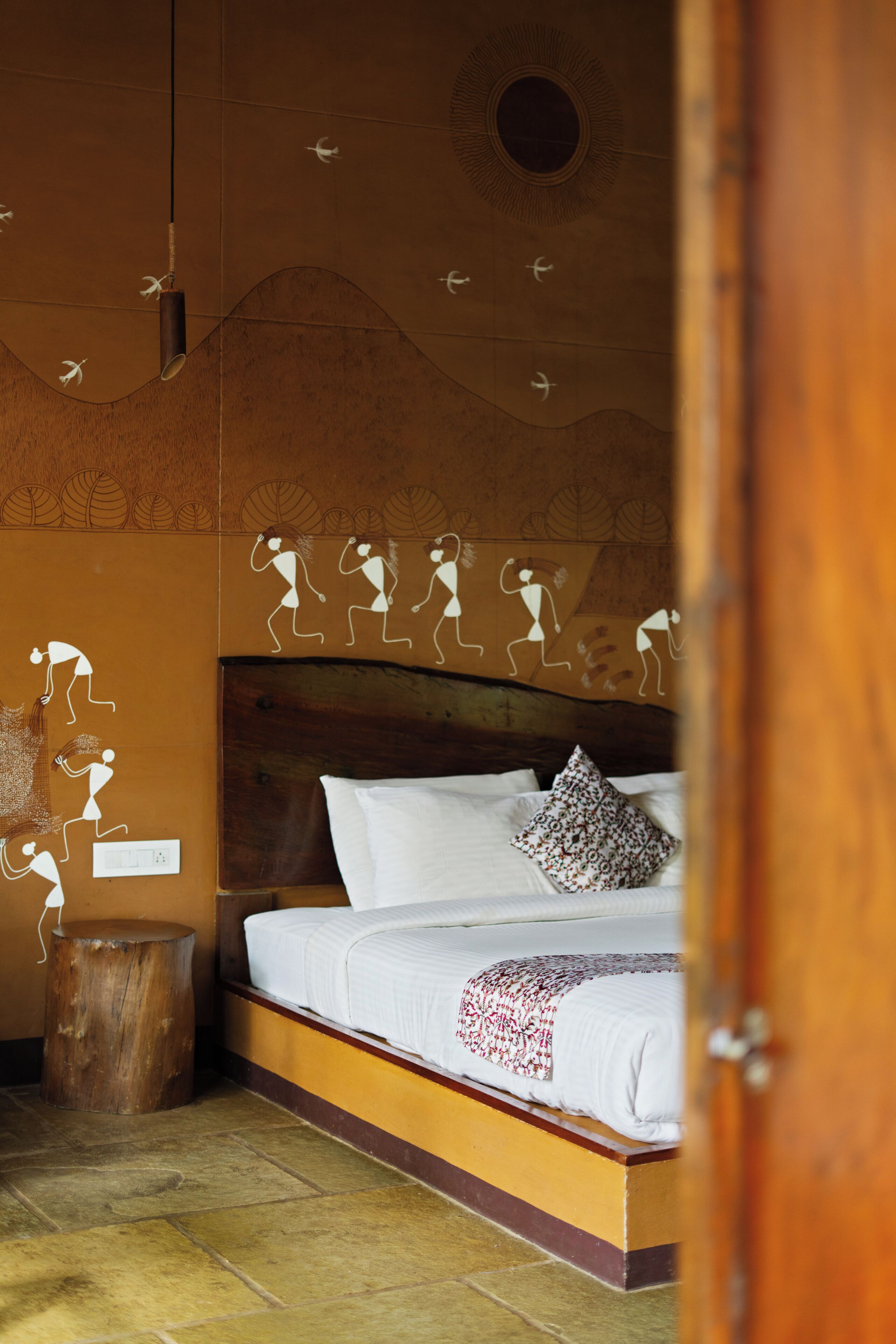 A bedroom with a bed, pillows, a nightstand, and a wall with a circular design.