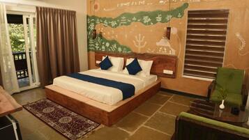 Un dormitorio con una cama grande, un cabecero de madera, una silla verde, una mesita con un florero y un mural en la pared.