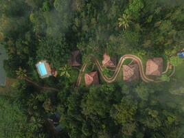 Vista aérea de un resort con un camino sinuoso, una piscina y varias construcciones tipo bungalow rodeadas de densa vegetaci ón tropical.