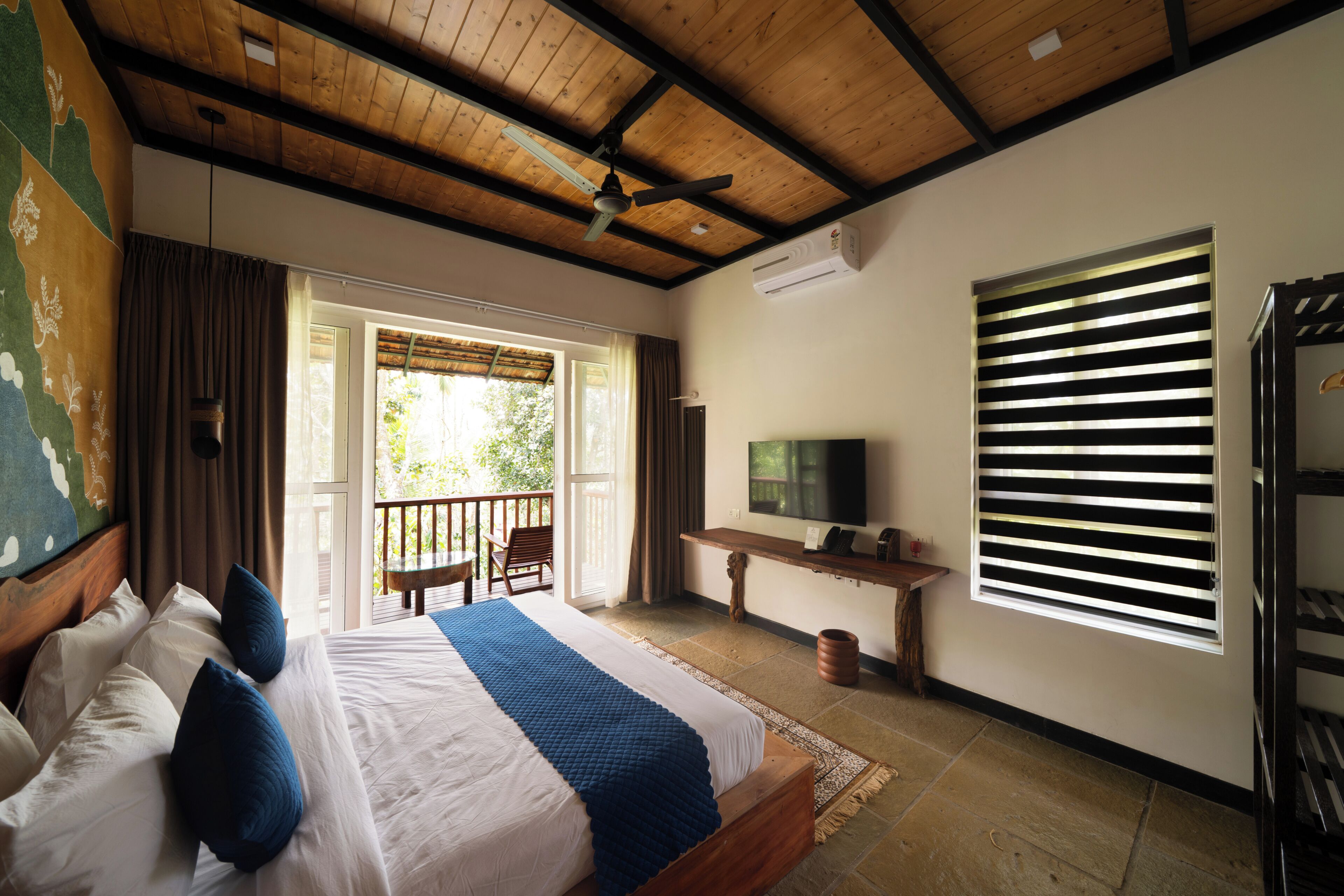 Una habitación de hotel con cama, televisión, escritorio y balcón.