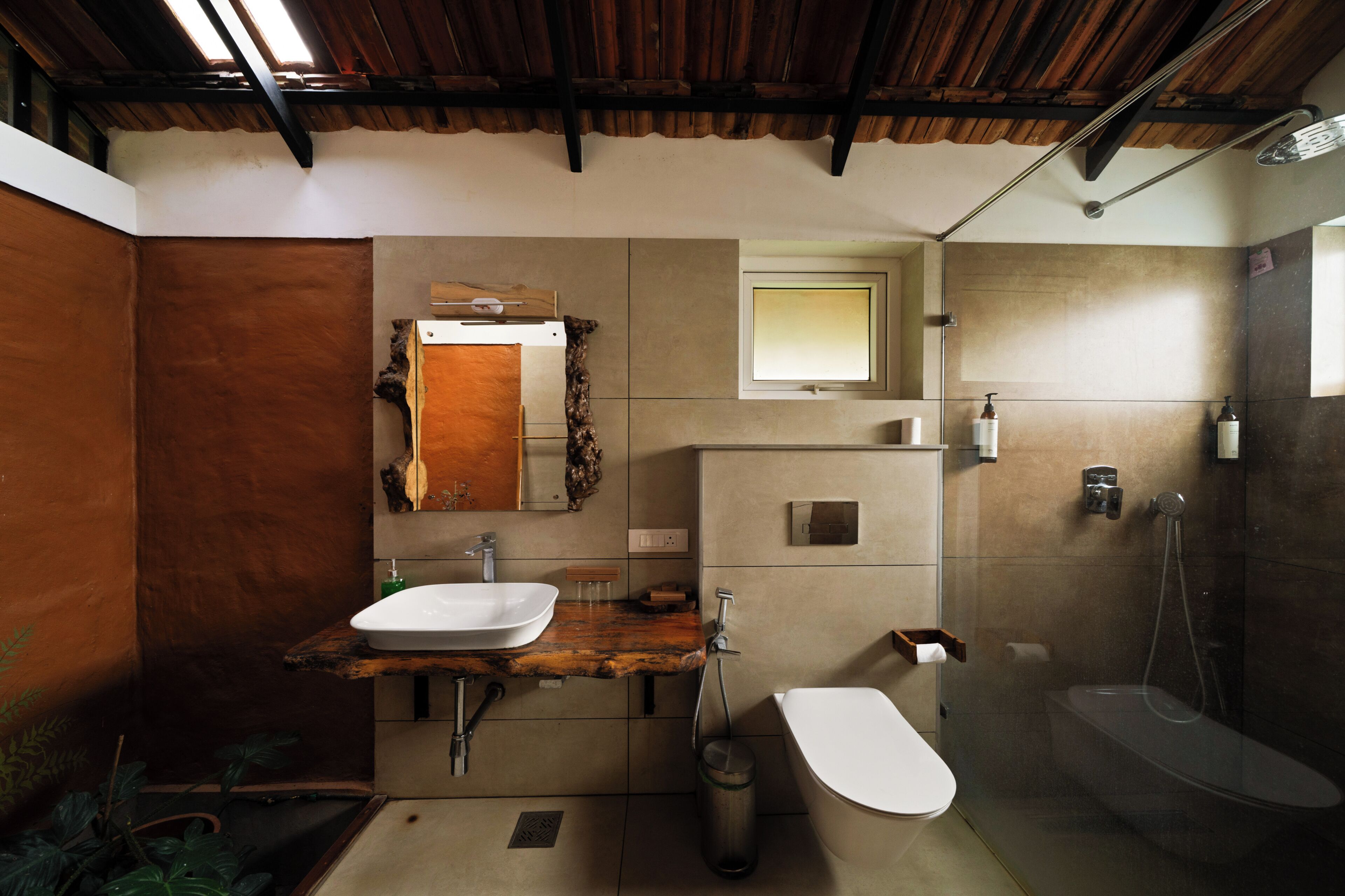 A bathroom with a wooden vanity, a white sink, a mirror, a toilet, and a shower area.