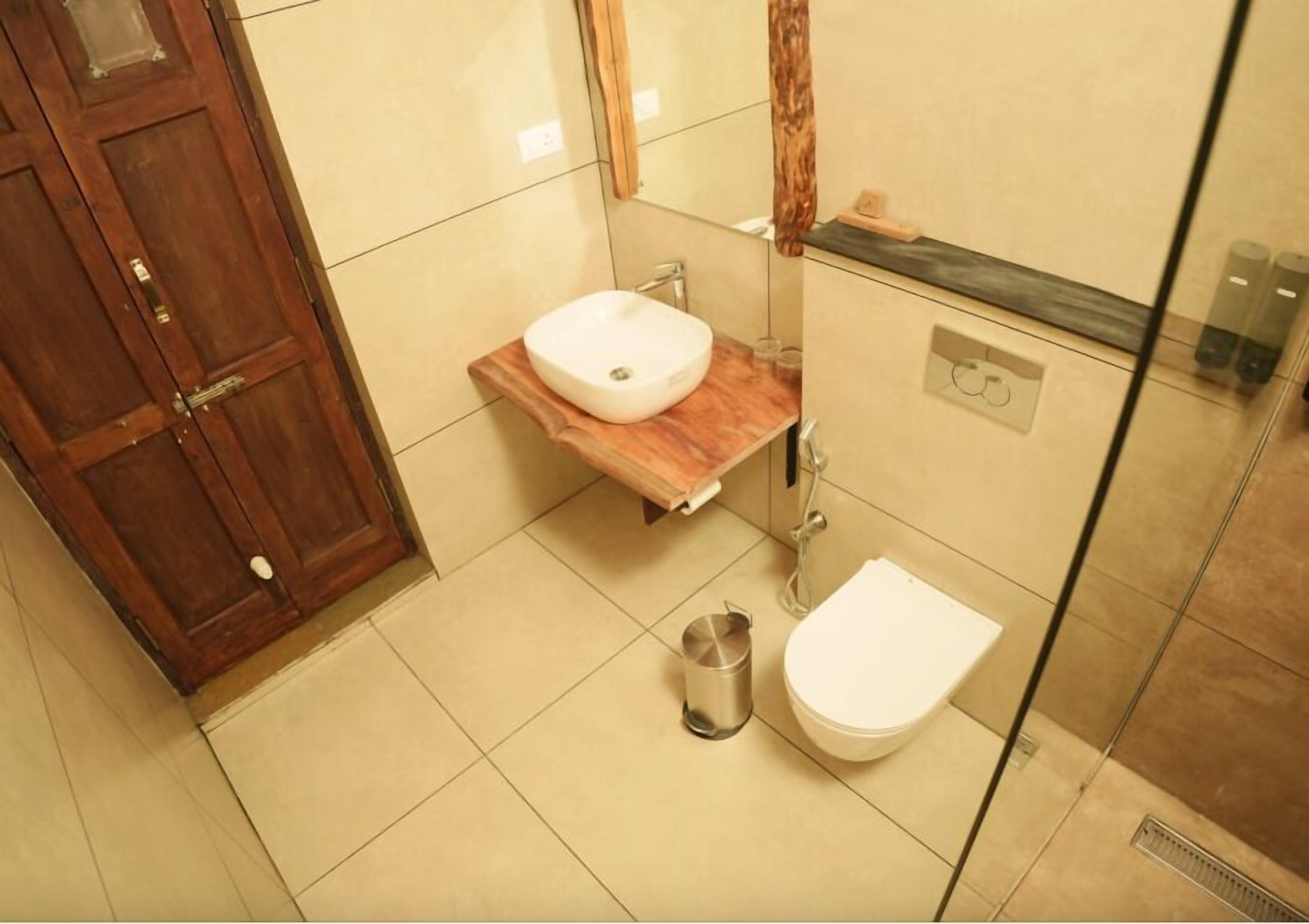 Un baño con tocador de madera, lavamanos blanco, inodoro y ducha.