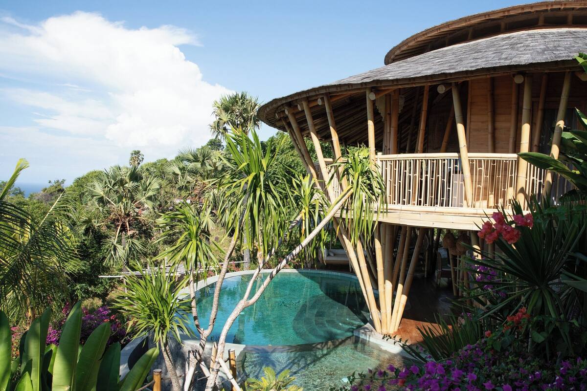 Ein Resort mit Pool, üppiger tropischer Vegetation und einem Holzbau mit Balkon.