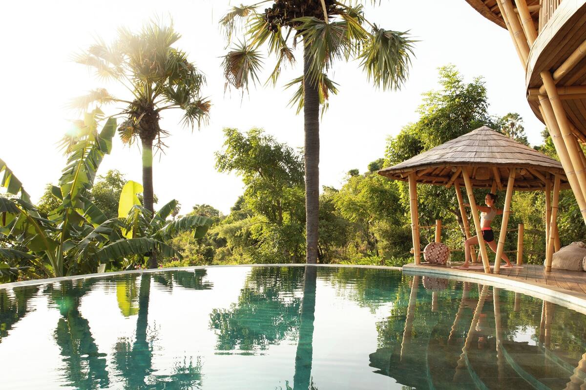 Ein Pool mit klarem Wasser, umgeben von üppiger Vegetation und einer Bambuskonstruktion.