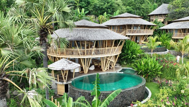 A resort with multiple wooden bungalows, a central pool, and lush tropical vegetation. - Villas Bukit Lipah (Karangasem)