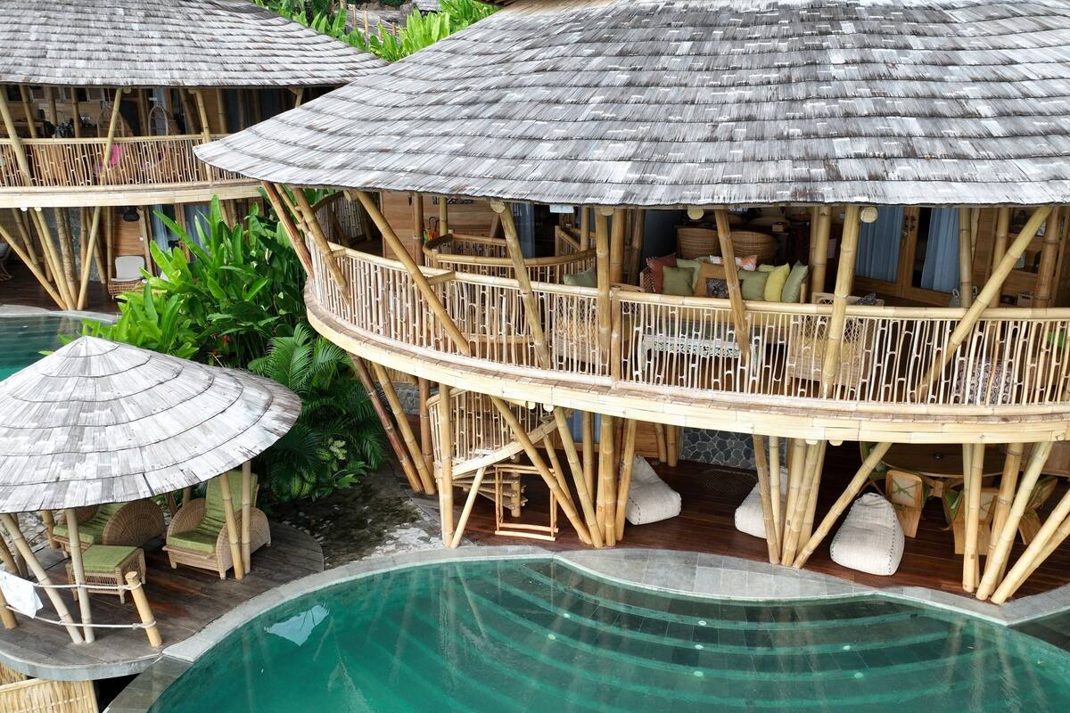 Ein Resort mit mehreren Bungalows über dem Wasser, ausgestattet mit Bambusarchitektur, Sitzgelegenheiten im Freien und einem Pool.
