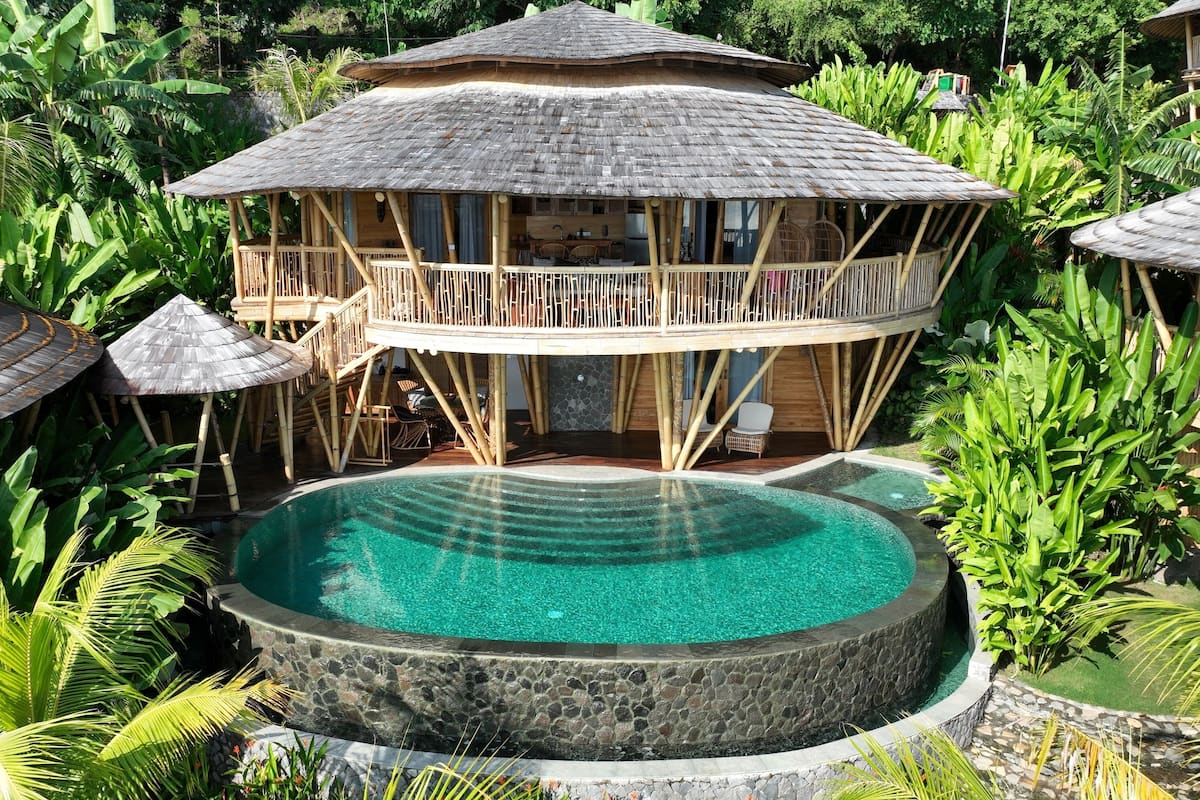 Ein Resort mit einem zentralen Pool, Holzbauten und üppiger Vegetation.