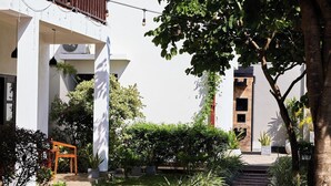 A modern building with a covered outdoor seating area, a stone pathway, and lush greenery. - Lum Residence (Ahangama)