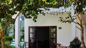 A courtyard with a pool, outdoor seating, and a building entrance. - Lum Residence (Ahangama)