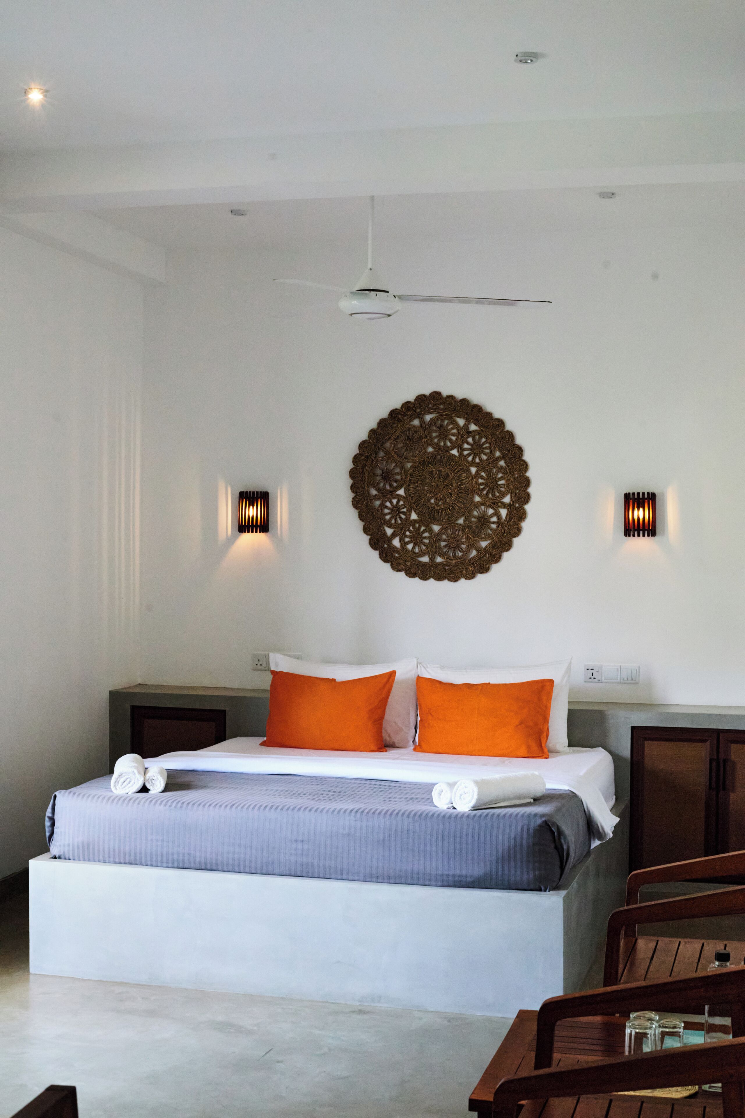 A bedroom with a bed, two bedside tables, a ceiling fan, decorative wall art, and two wall-mounted light fixtures.