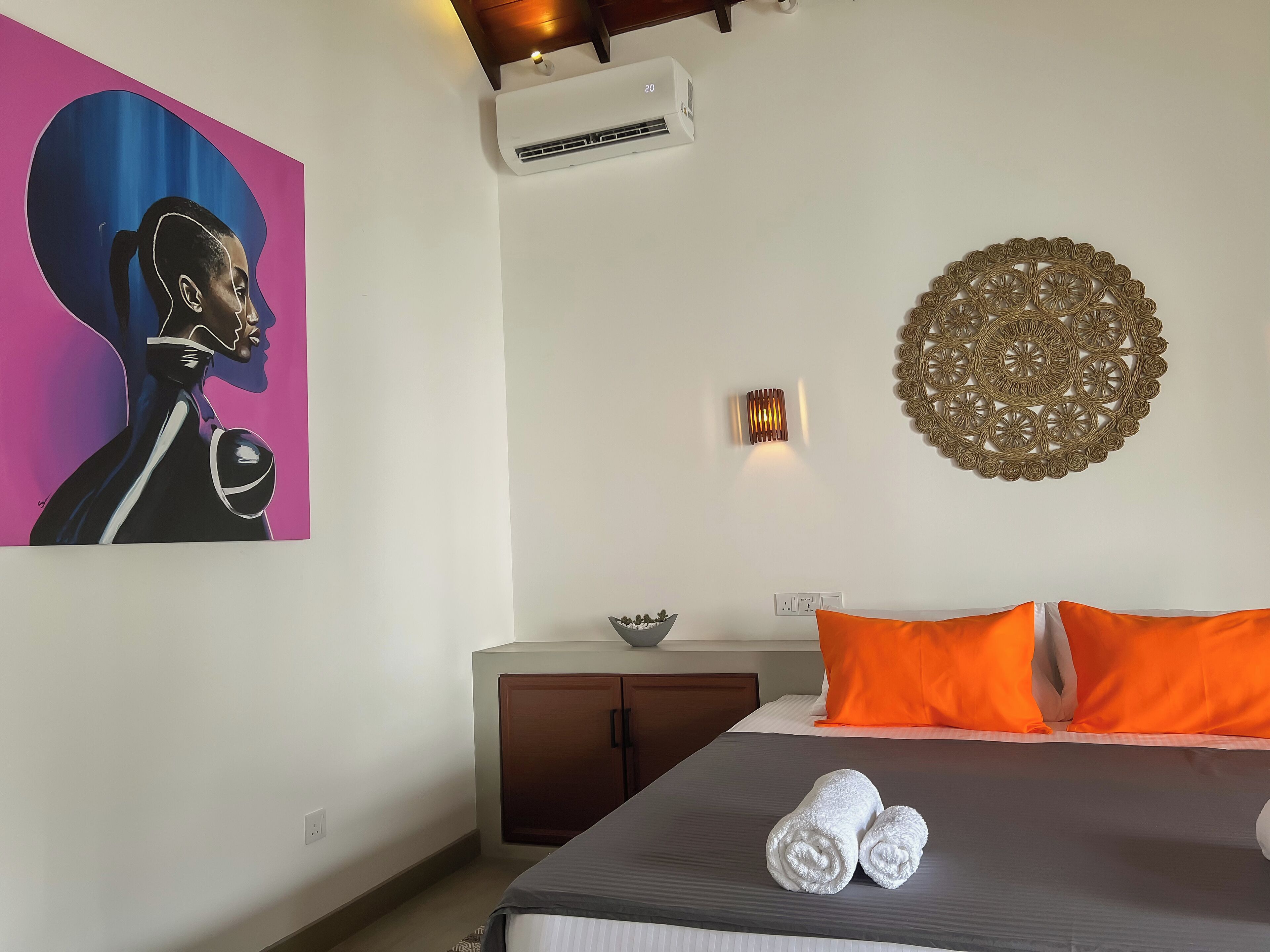 Una camera d'albergo con un letto, un condizionatore d'aria, un elemento decorativo a parete e un quadro.