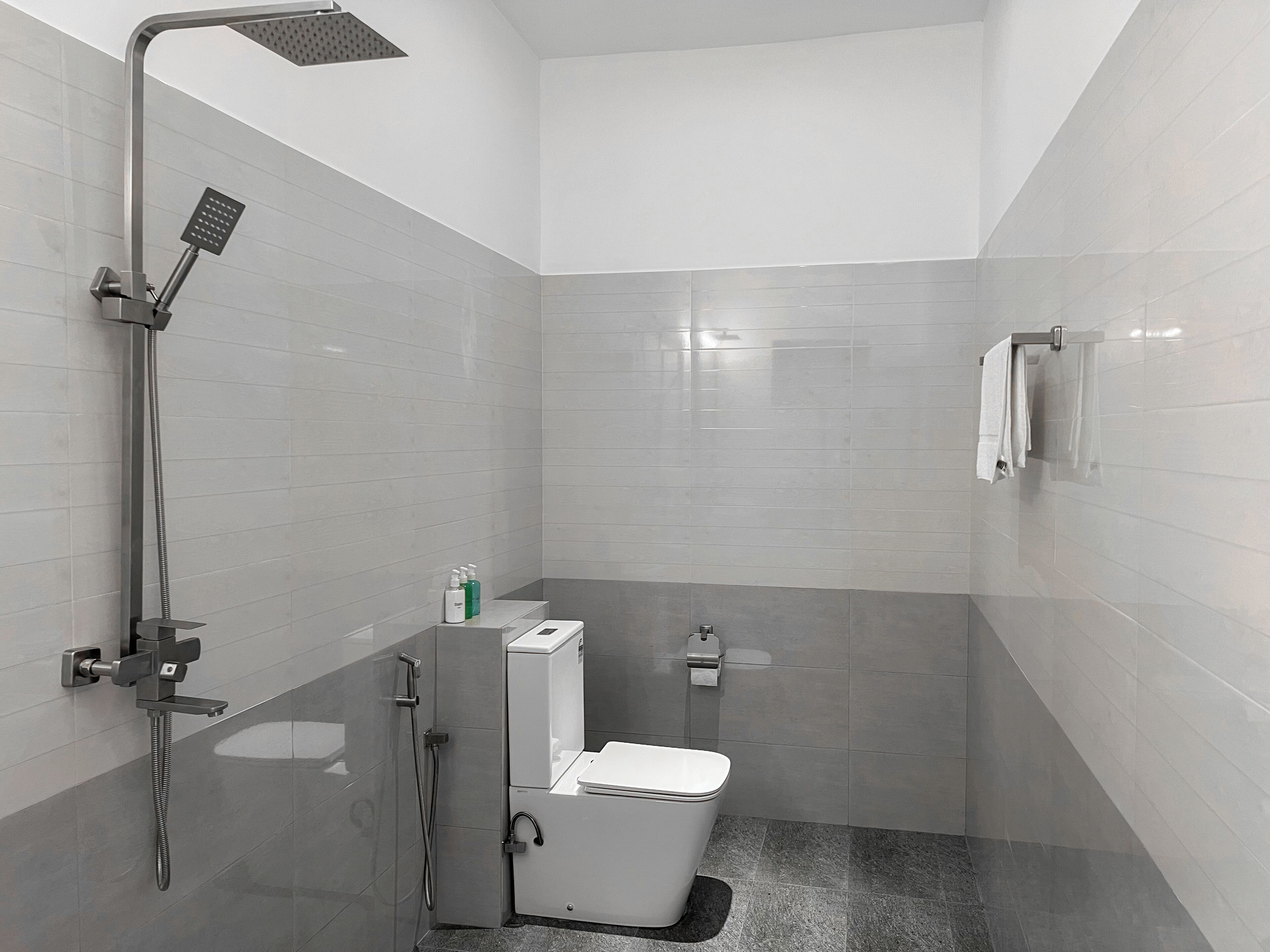 A modern bathroom with a shower, toilet, and towel rack.