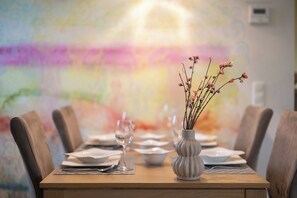 A dining table set with plates, cutlery, and a vase with flowers. - Vacation home Mellumplate 4 Ground floor and close to nature. (Wurster Nordseeküste)