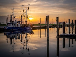 Ein Boot liegt an einem Steg, im Hintergrund versinkt die Sonne im Abendrot.