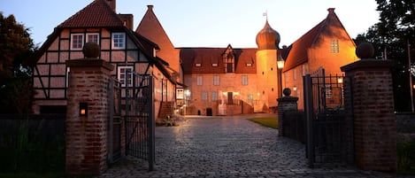 Un edificio histórico con entrada de adoquines, arquitectura tradicional y un camino de entrada con portón.
