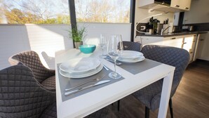 Un comedor con una mesa preparada para cuatro personas, una planta en maceta y vistas al exterior.