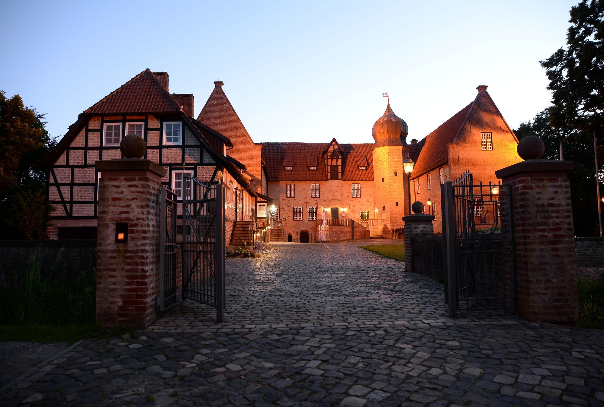 A historic building with a cobblestone entrance, traditional architecture, and a gated driveway.