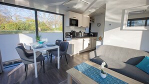 Una cocina moderna con armarios blancos, un microondas y un comedor con mesa y sillas.