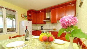 A dining table with a fruit bowl, a wine glass, and a vase with flowers.