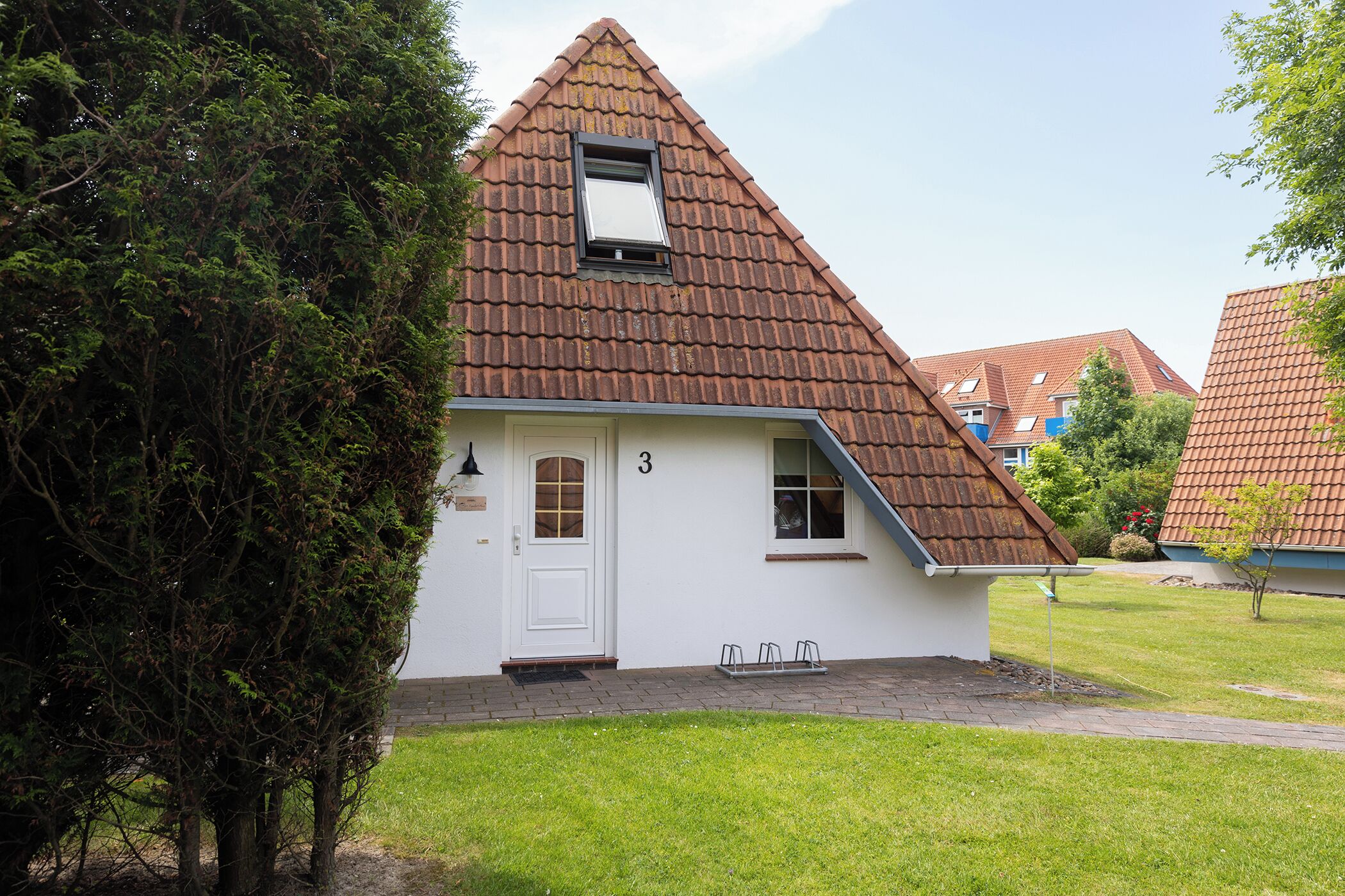 Ein kleines, eingeschossiges Haus mit einem geneigten Dach und einer weißen Tür.